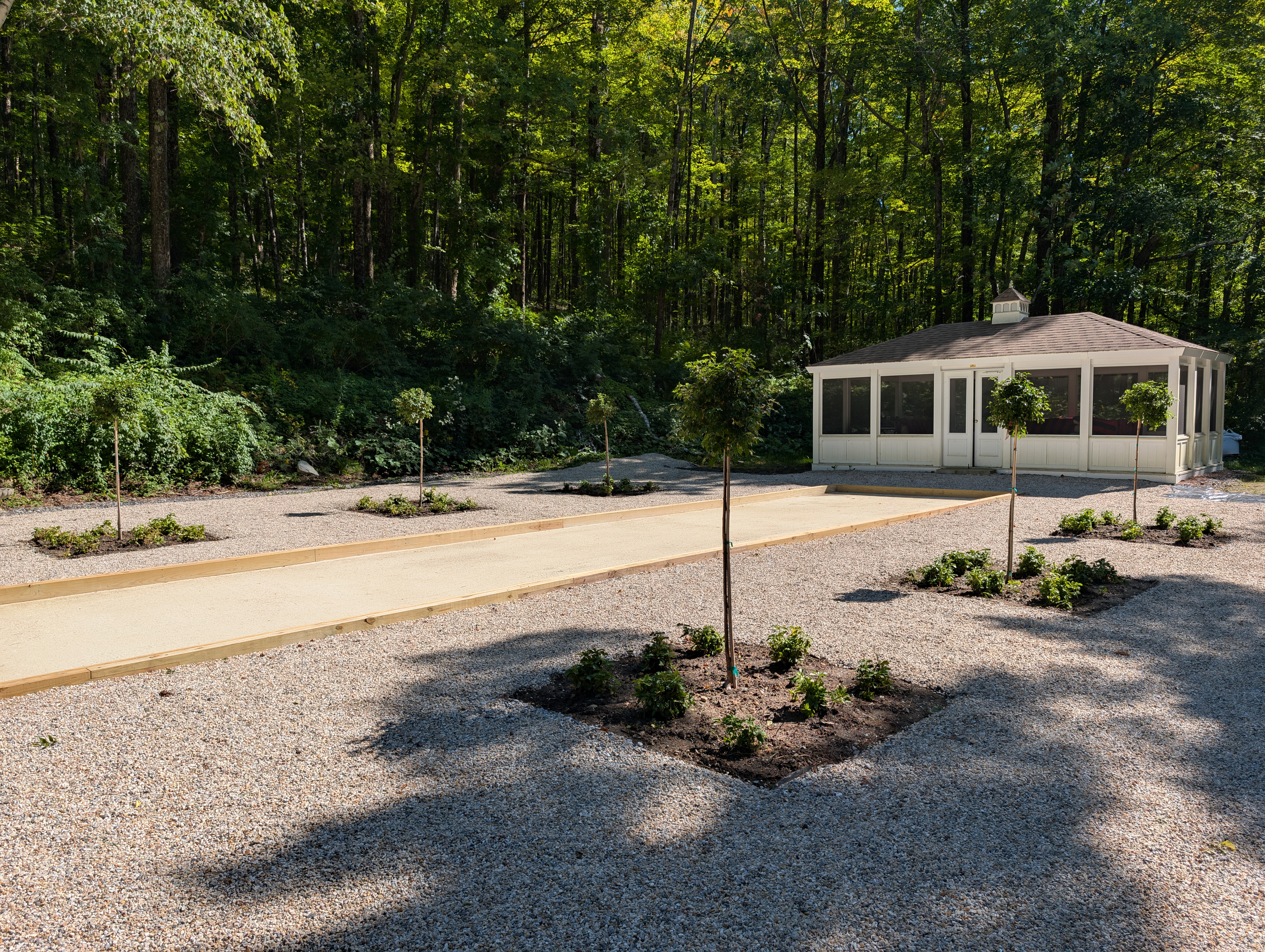 Custom landscape installation with bocce court and ornamental birch