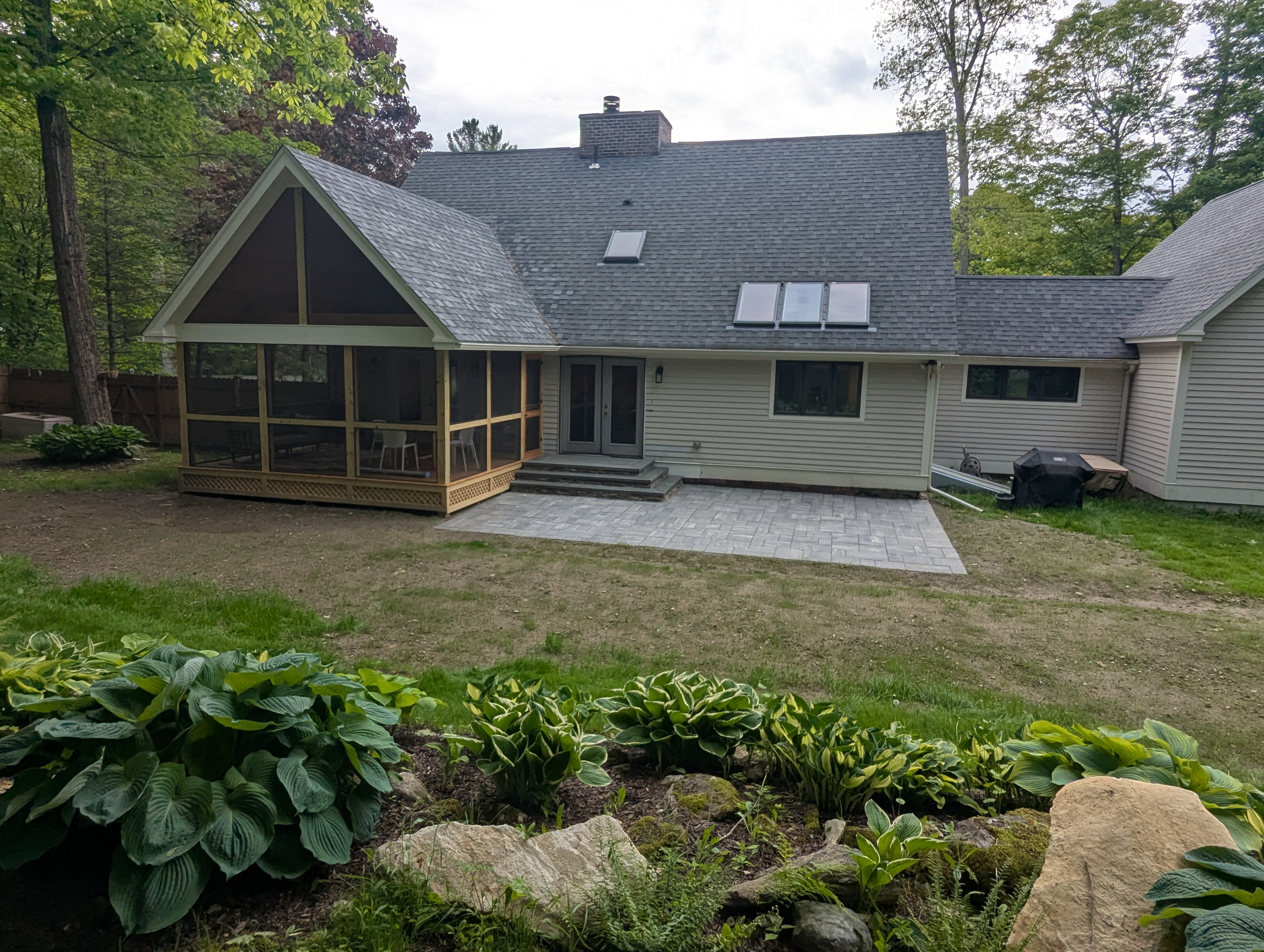 Custom screened porch addition with bluestone landing, stone veneer, and Unilock paver patio